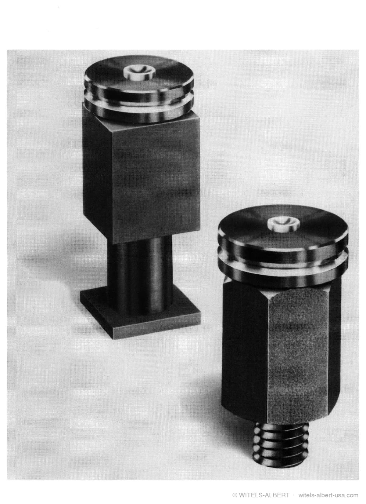 Photograph of two WICAS cassette straightening rolls — grooved straightening sheaves on sealed cassette housings, one with a square block body and one with a hexagonal threaded body.