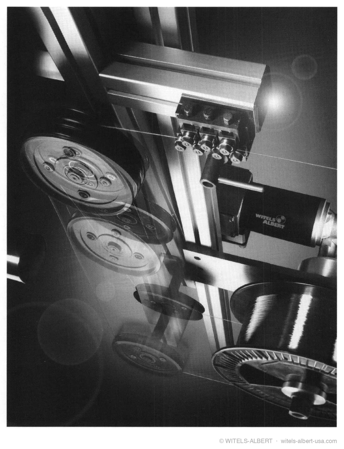 Photograph of a WITELS-ALBERT decoil-straightener from below, showing deflection pulleys, a straightening unit on an aluminum profile frame, and wire spools.