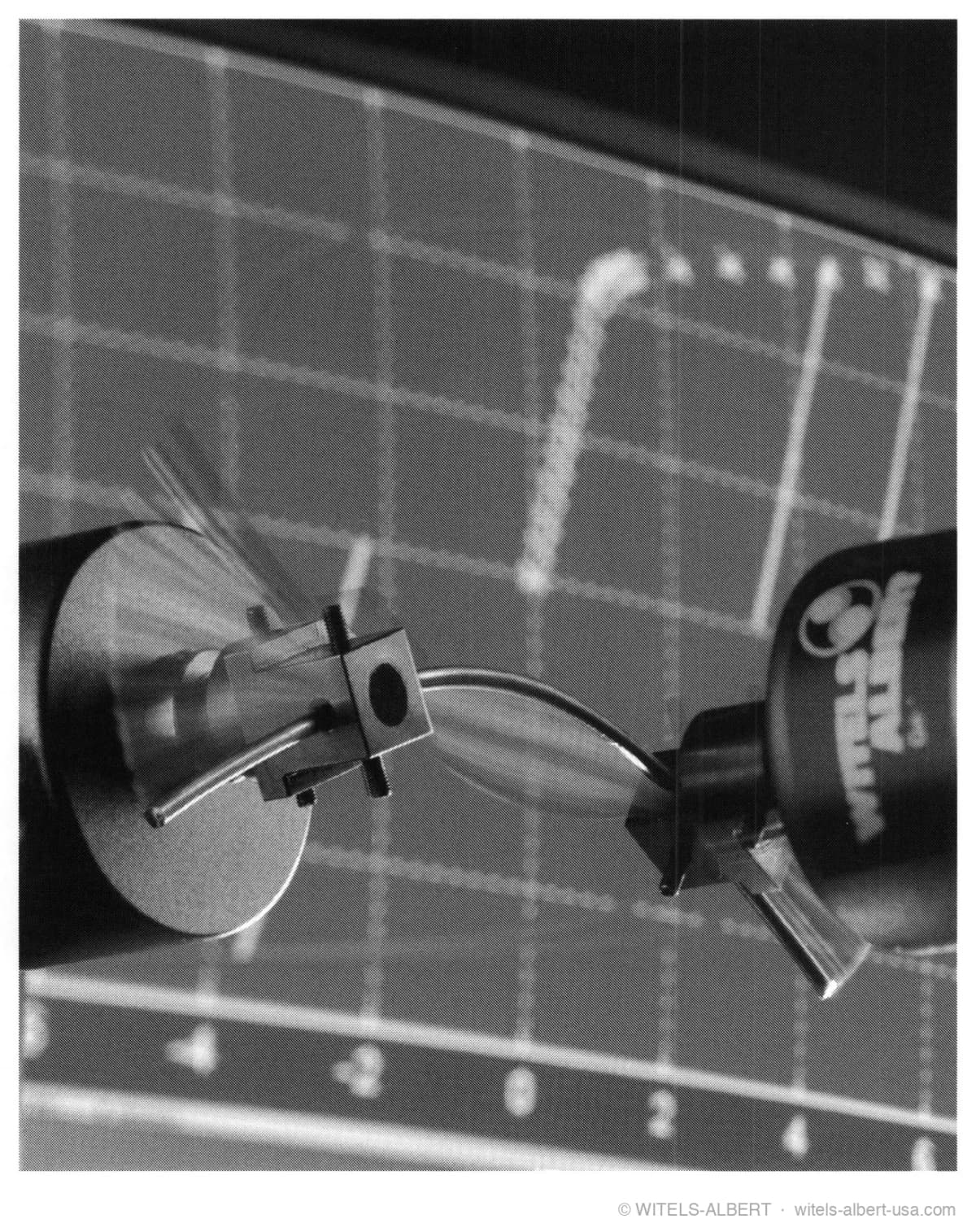 Photograph of a WITELS-ALBERT diagnosis unit bending a wire sample between two clamping heads in front of a measurement grid.