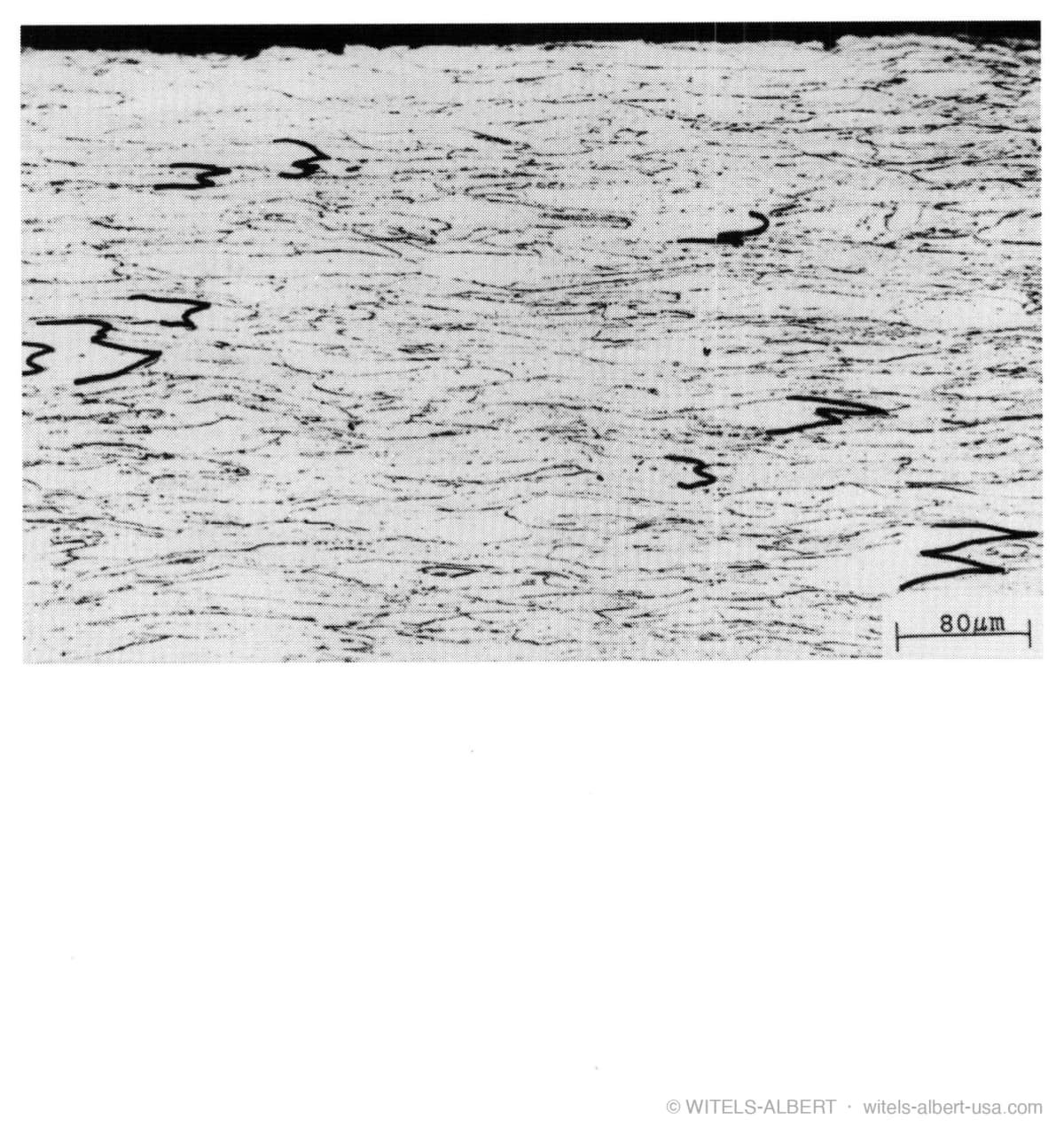 Micrograph of a drawn wire's microstructure with grains elongated in the drawing direction, at a scale of 80 micrometers.