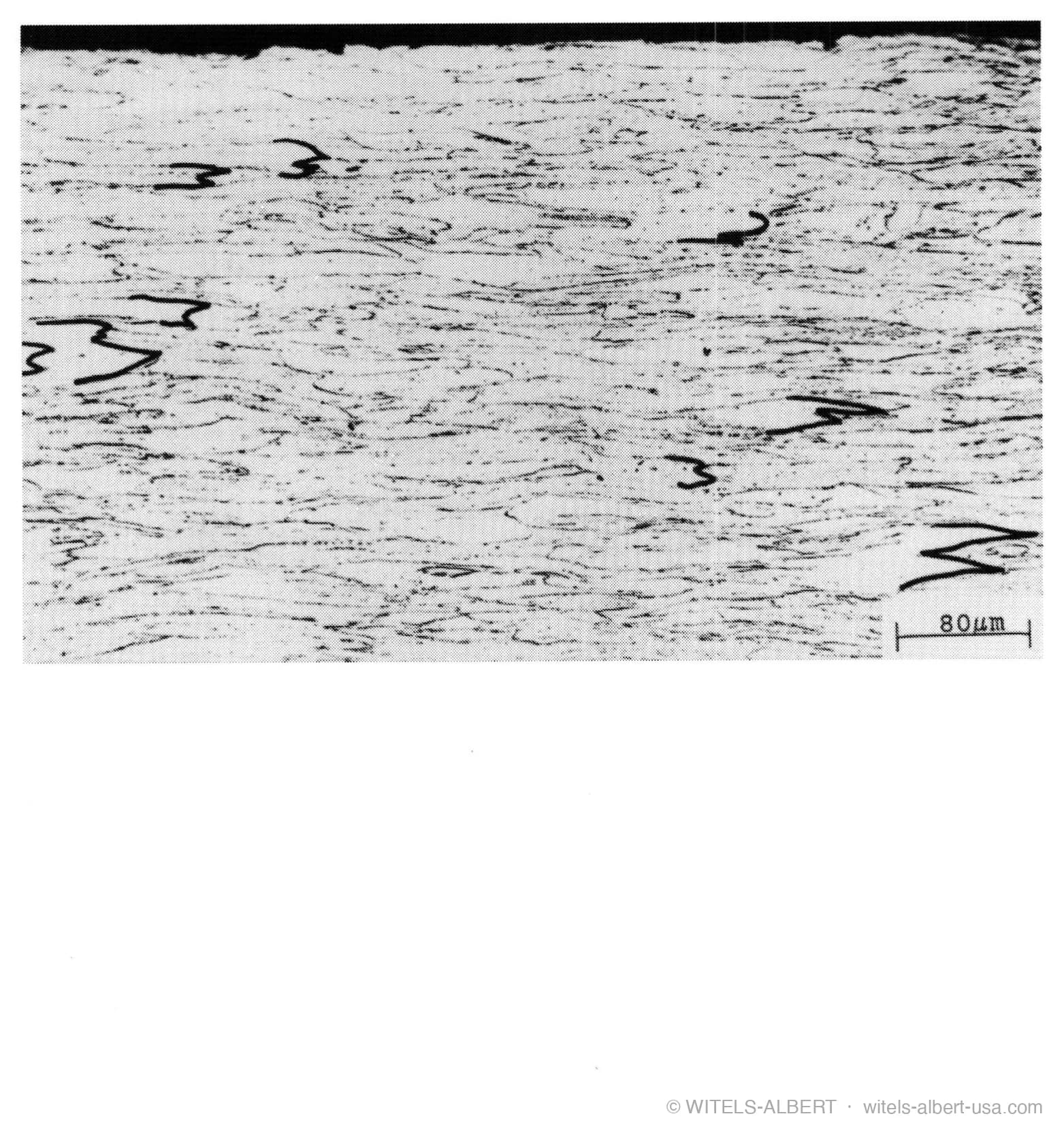 Micrograph of a drawn wire's microstructure with grains elongated in the drawing direction, at a scale of 80 micrometers.