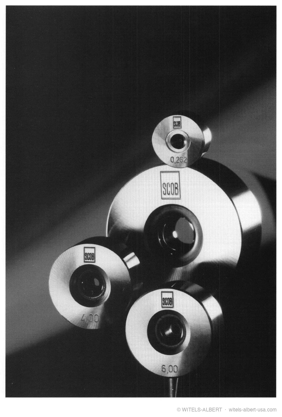 Photograph of four polished wire-drawing dies of different hole diameters, stamped with their sizes.