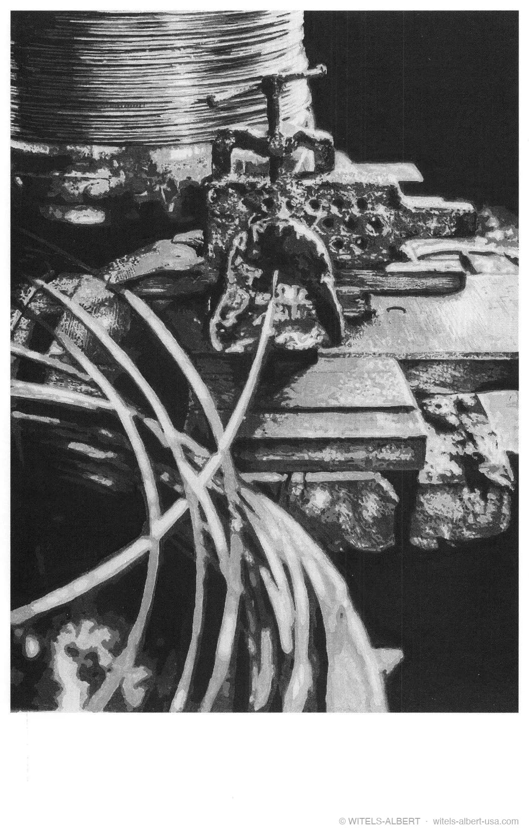 High-contrast photograph of a historical wire-drawing station with wires running from a coil through a clamped drawing tool.