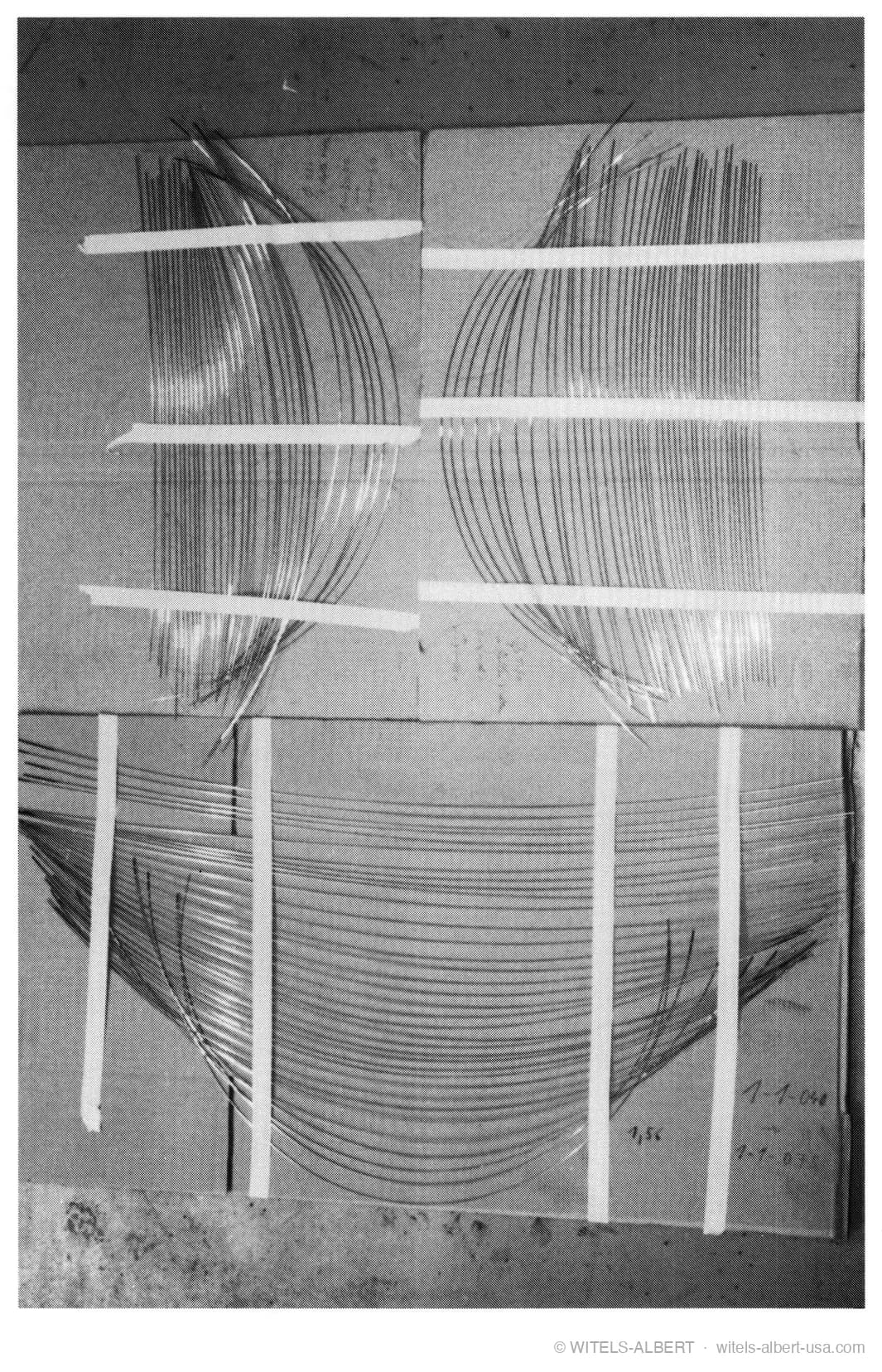 Photograph of wire sample bundles taped to cardboard sheets, showing visibly different curvatures between the bundles.