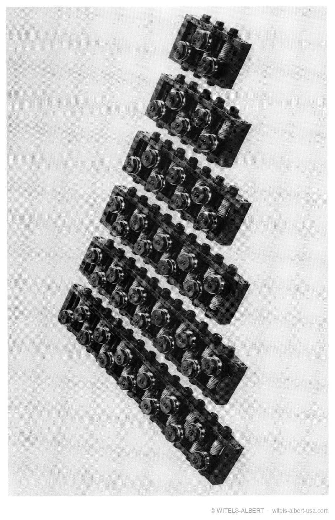 Photograph of six roll-type straighteners of increasing length, from a compact unit with few straightening rolls to a long unit with many.