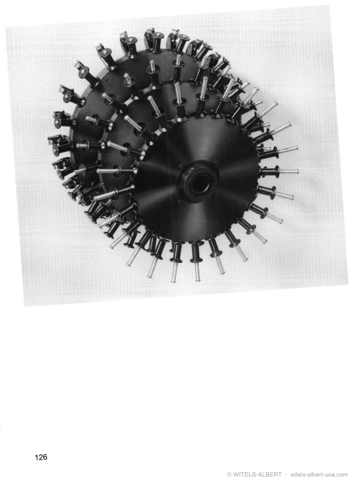 Photograph of three preforming heads of different sizes, each a disc ringed with radially mounted bending rolls, nested together.