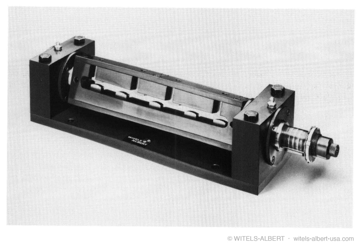 Photograph of a rotary straightening unit: a spinner with internal straightening tools mounted between two bearing blocks on a base plate, with a drive shaft at one end.