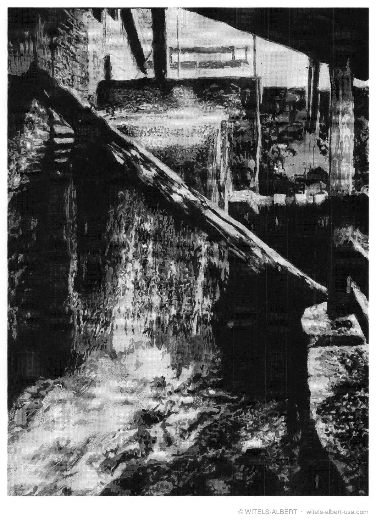 High-contrast photograph of a historic water wheel with water rushing over its wooden channel inside a mill.